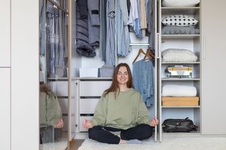 Decluttering tips: Cheerful female in lotus position at modern wardrobe storage. Happy housewife posing meditating