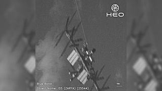 a black and white image of the international space station showing solar panels and trusses. to either side of the image are blurry copies