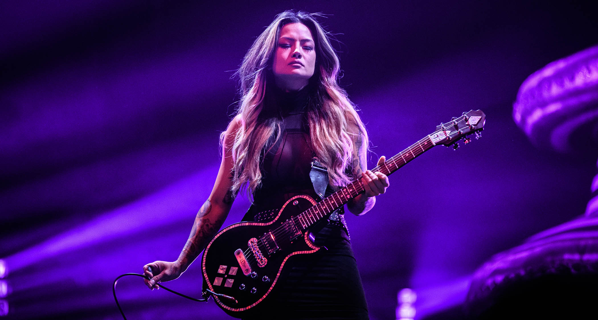 Kiki Wong is bathed in purple light as she plays a Zemaitis singlecut live with the Smashing Pumpkins.
