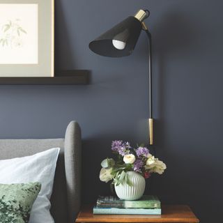 bedside table with black lamp and vase of flowers