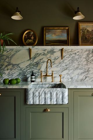 khaki green kitchen with marble splashback and wall lights