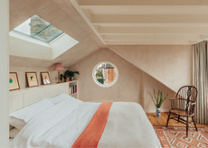 a beautiful loft bedroom with clay colored walls a low bed and a circle window and a roof window