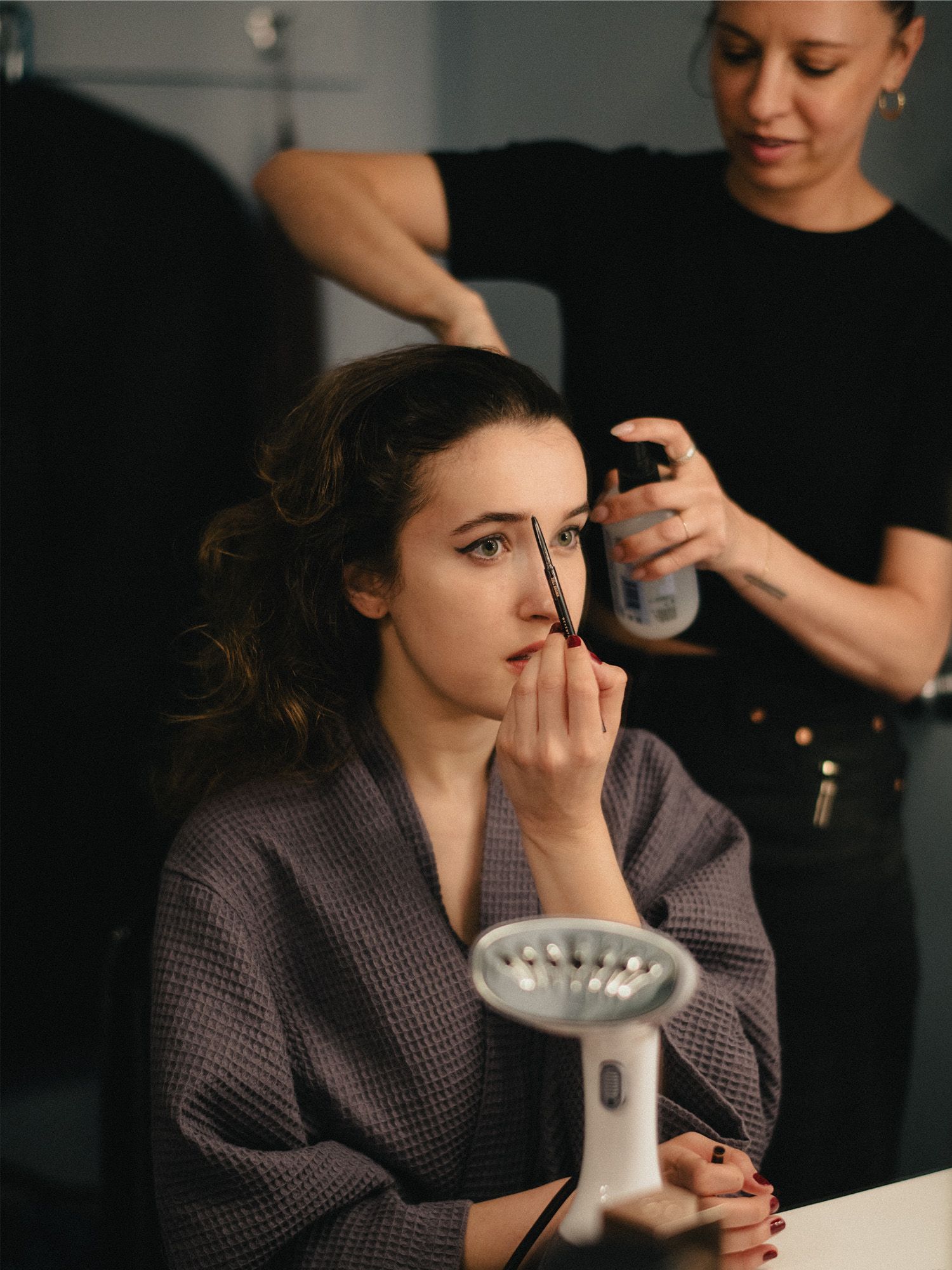Gracie Lawrence gets ready for the 2025 Tony Awards. She is penciling her brows while her hairstylist preps her hair.