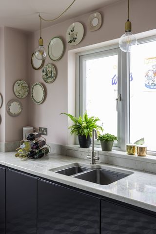 A shot of the kitchen sink, fitted in a marble-effect worktop over deep blue kitchen units