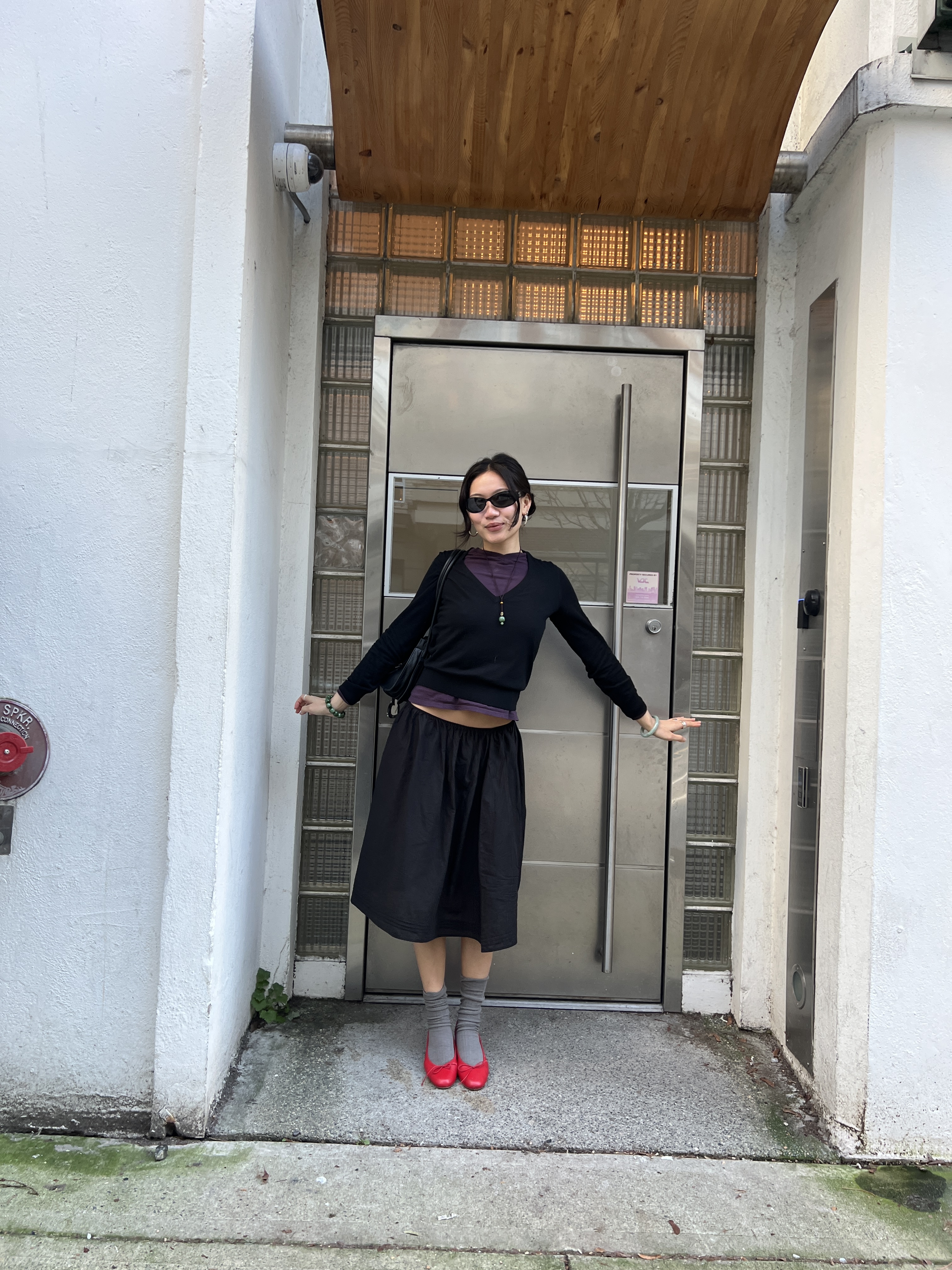 Vivian Li wearing a black outfit outside a steel door