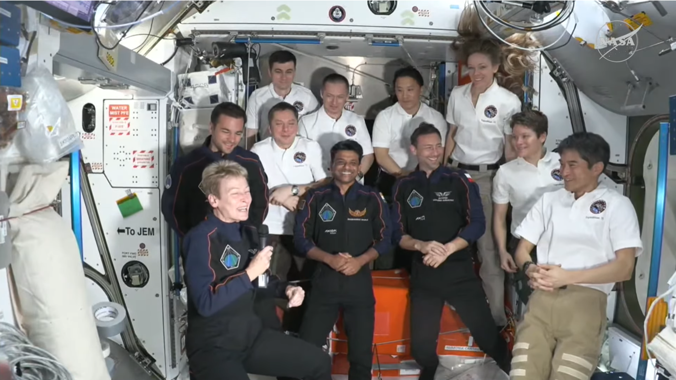 A group of people float in a space station module.