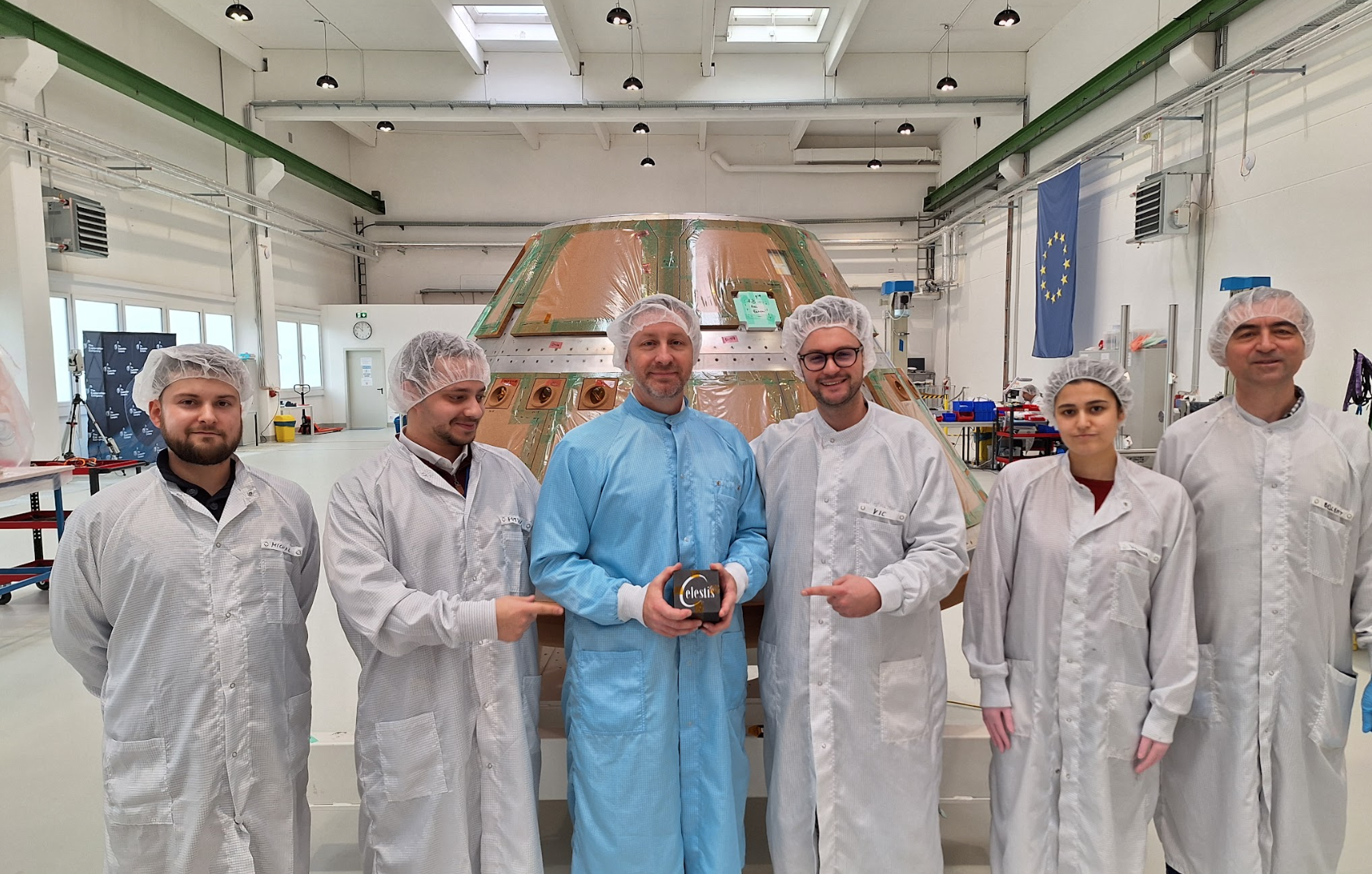 Six scientists in lab coats at an aerospace facility