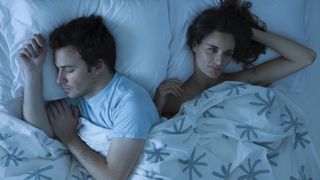 A woman lies in bed next to her partner because she is unable to sleep