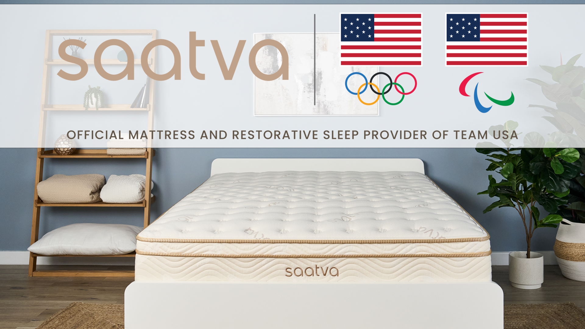 The Saatva Classic mattress on a bed frame in a bedrom. At the top of the image is the Saatva logo, the Team USA Olympic and Paralympic logo, and the words "Official mattress and restorative sleep provider of Team USA"