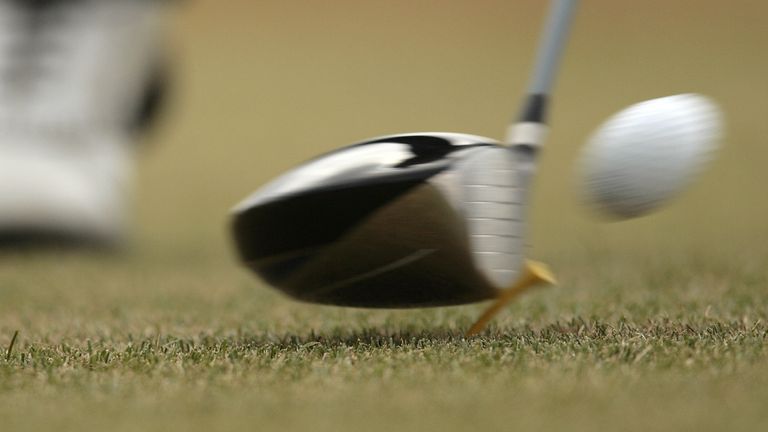 A close up of a club hitting a golf ball of a tee