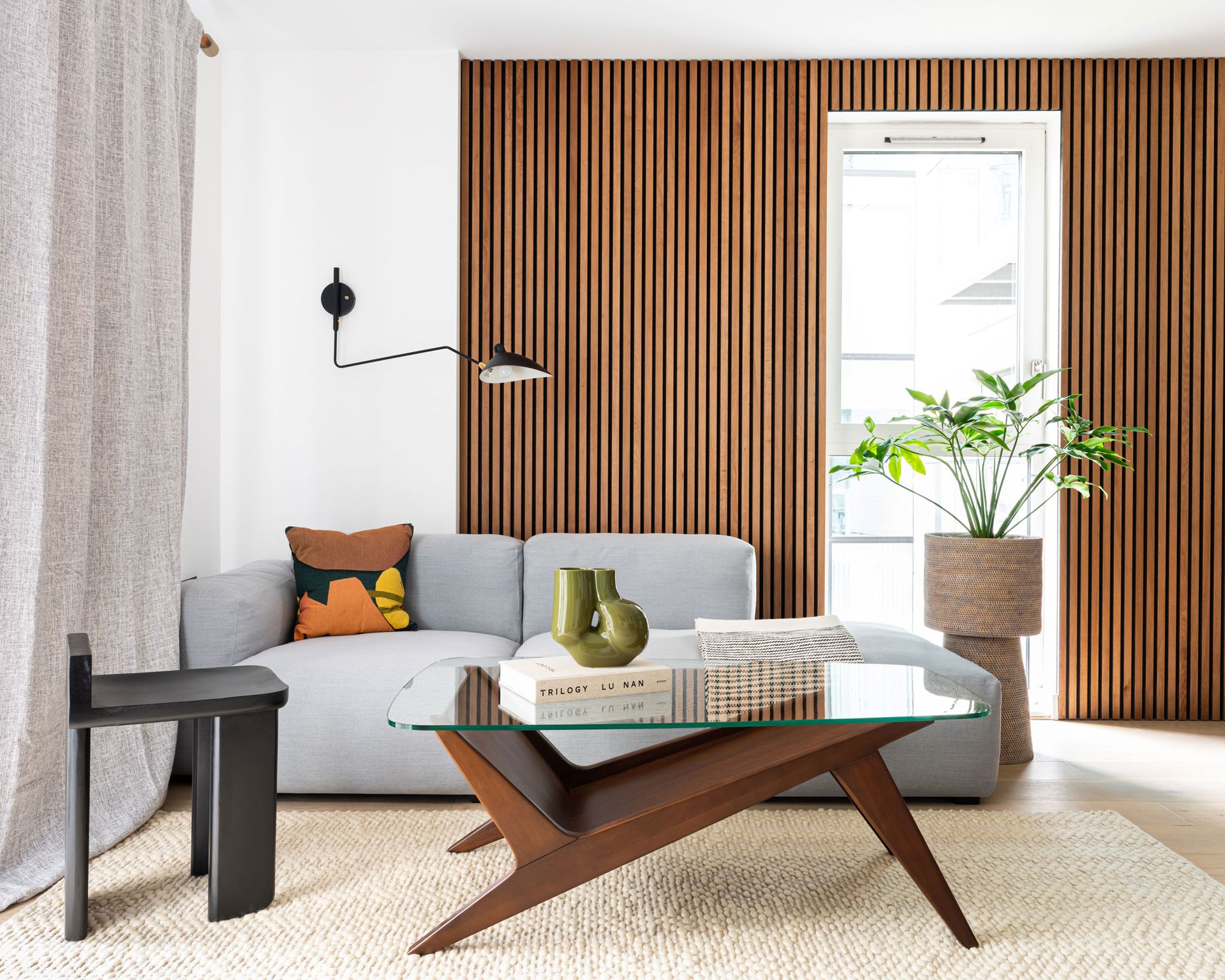 living room with biege rug, midcentury coffee table, blue sofa and wooden panelling