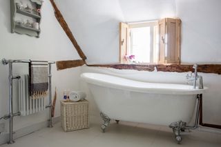 roll-top slipper bath in listed thatched cottage with beams