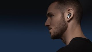 A moodily lit photo showing a young stubbly man with a Status Pro X earbud in his ear and a frown on his face. Maybe he's listening to something bad like Toploader.