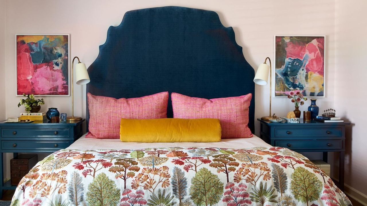 Bedroom with pale pink walls, dark navy headboard and nightstands, floral bedding