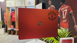 Microsoft Surface Laptop 13-inch 2nd Edition with Manchester United and Qualcomm Snapdragon branding on a red chassis, displayed with football imagery