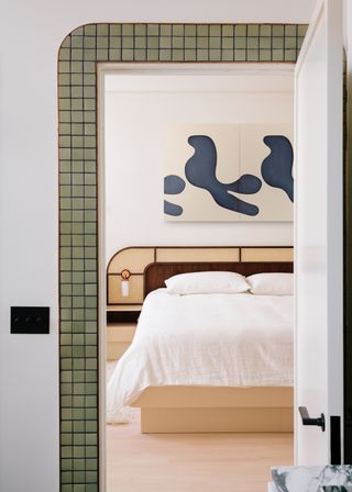 A bedroom with a door frame in green tiles