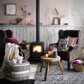 A pale pink living room with brown armchairs either side of a log burner