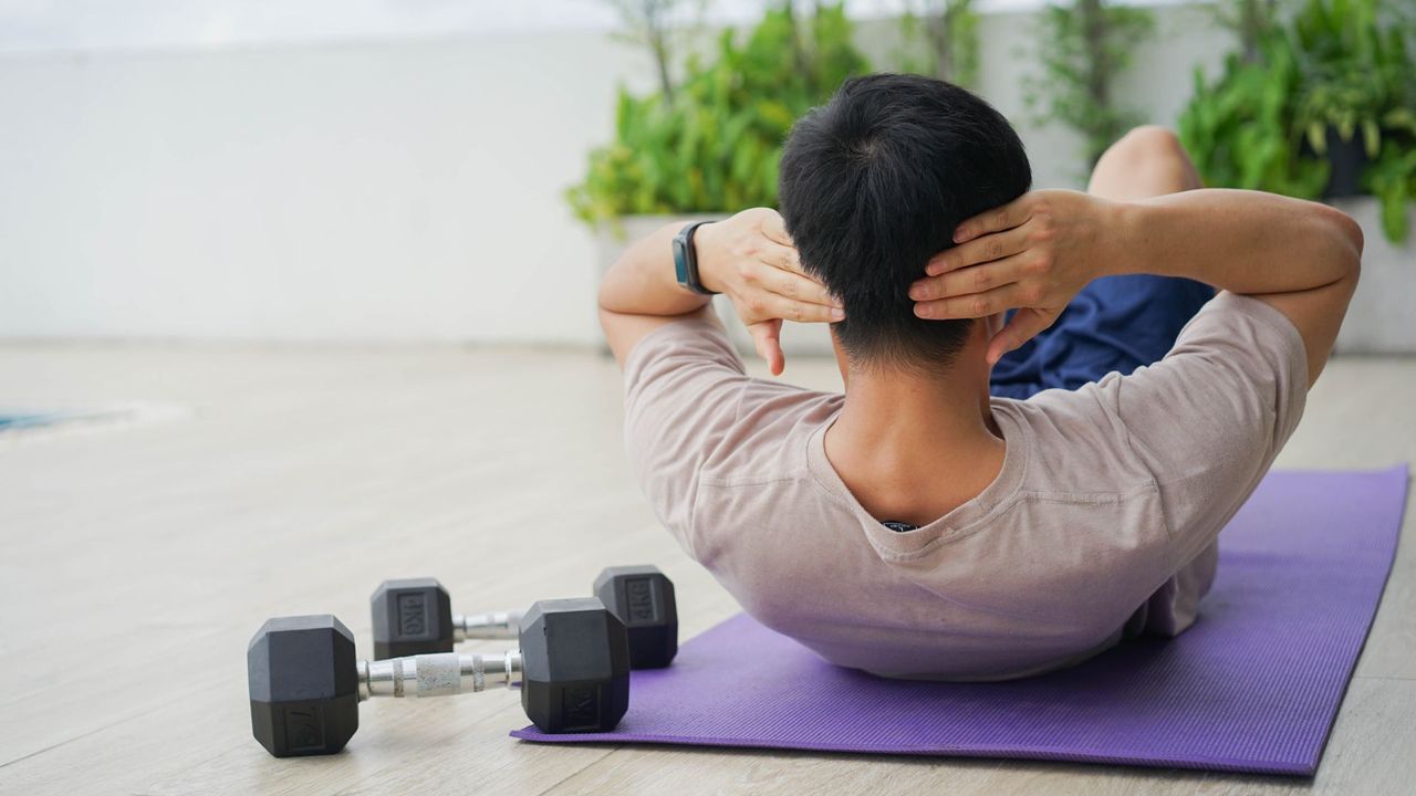 A man completing an abs workout with dumbbells