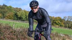 Male cyclist riding out of the saddle on a Cervelo Caledonia-5 wearing a black Castelli Squall shell