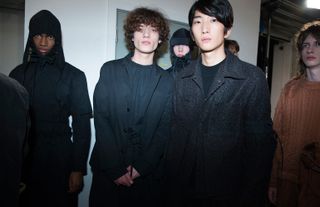 Three models stood wearing black coats