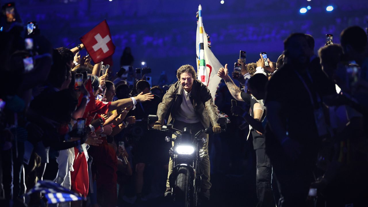 Tom Cruise exits Stade de France with Olympic flag