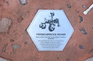 a hexagonal silver plaque celebrating the accomplishments of nasa's perseverance mars rover.