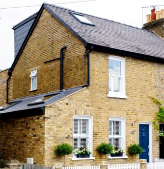 house with stone wall and blue door white window with plant