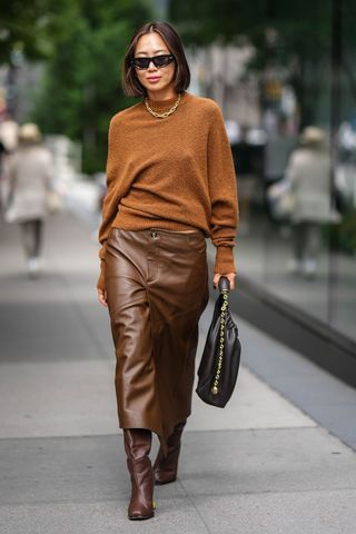 Street style image of a woman wearing knee high brown boots