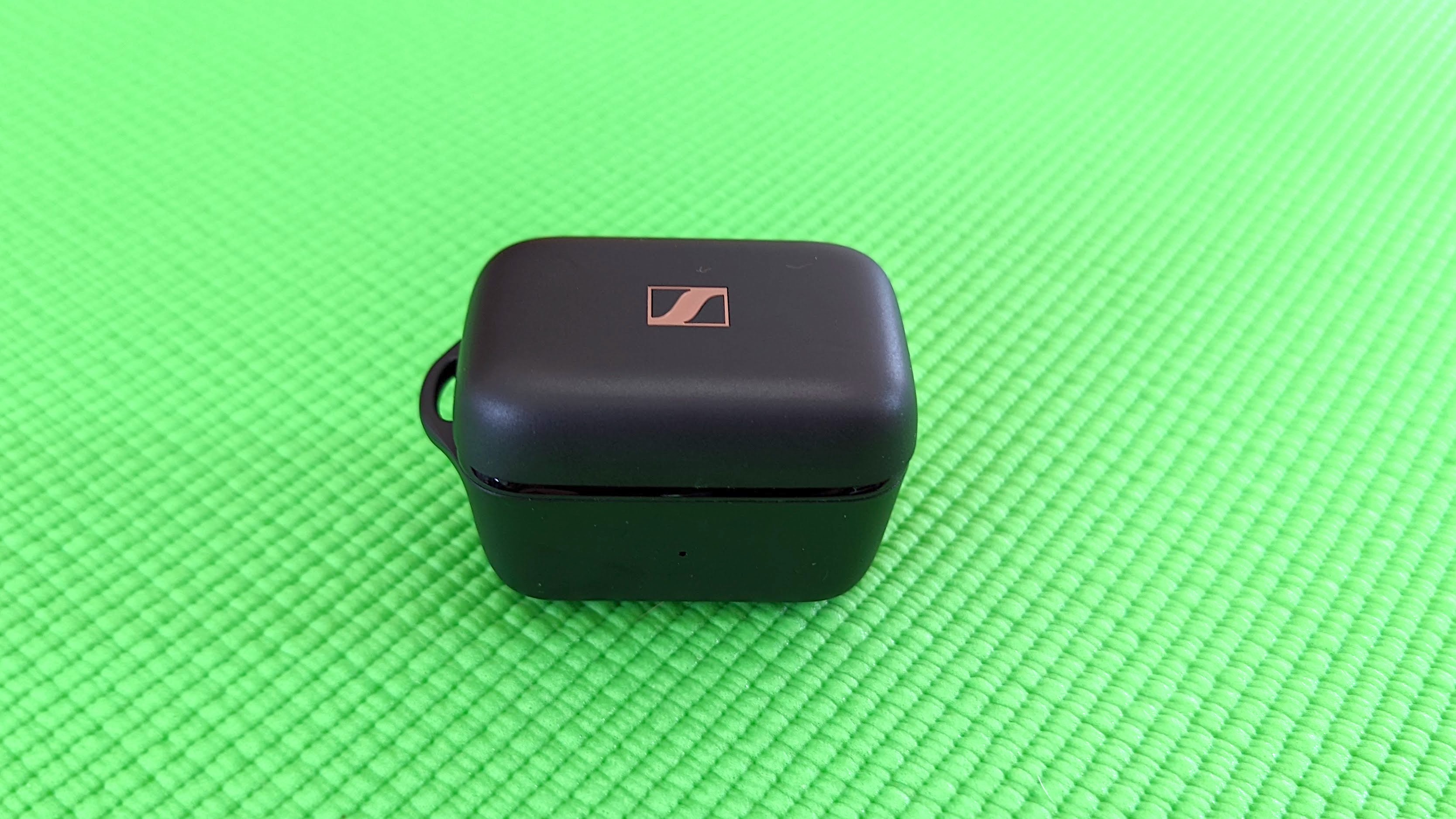 The Sennheiser Sport True Wireless charging case sitting on a green yoga mat