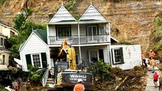 A damaged property where a man was found dead after a landslide in Auckland, New Zealand