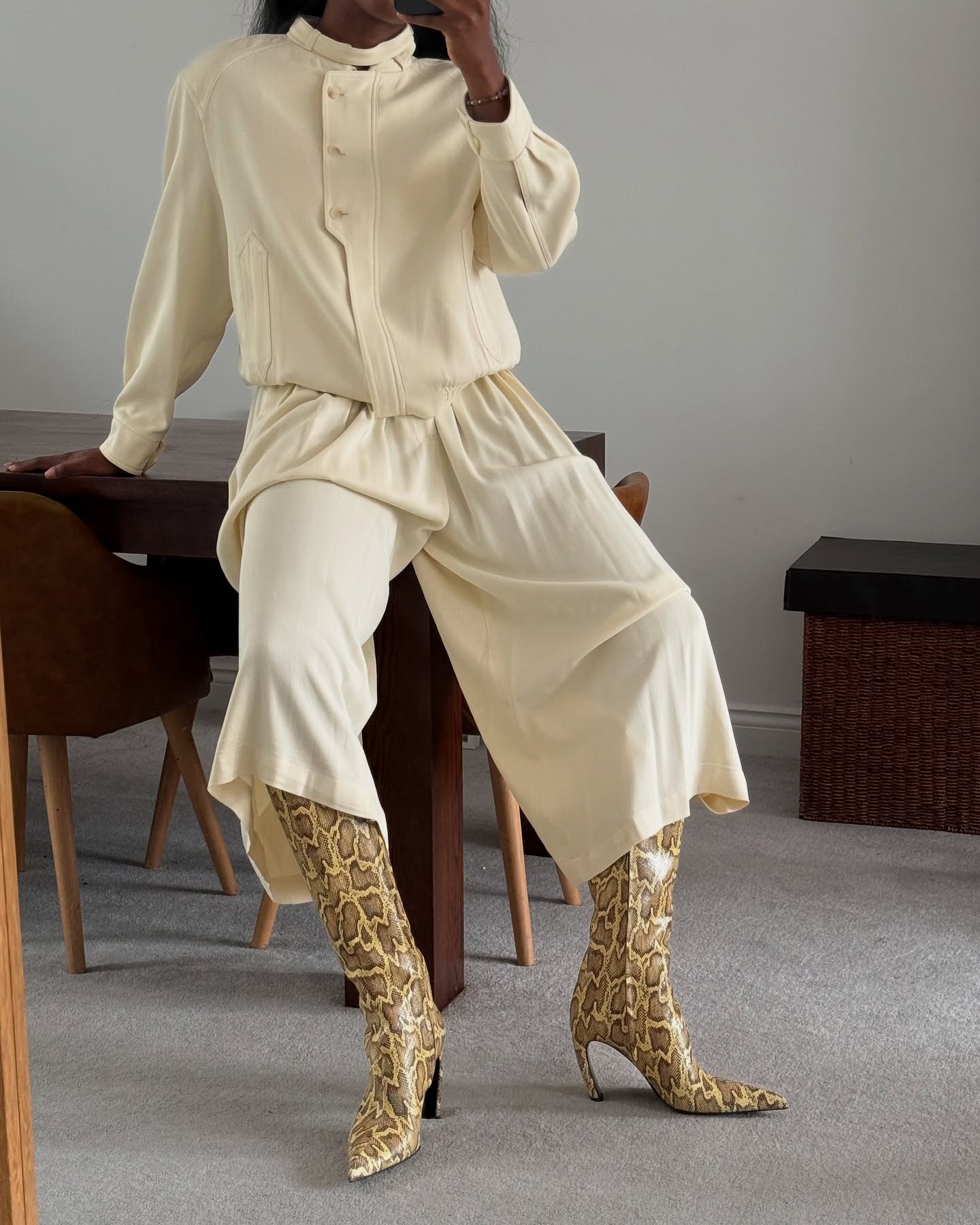 Influencer @nlmarilyn wears snakeskin print boots with cream longline shorts and a cream bomber jacket.