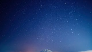 a starry night sky above a snow-capped mountain