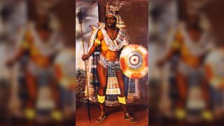 Portrait of Moctezuma II (1466-1520). Here we see a muscular man holding a long spear in one hand and a round white, red and orange shield in the other. He is also wearing a loin cloth around his waist, a long cloak drapped around his shouders and an elaborate gold and blue headdress with feathers.