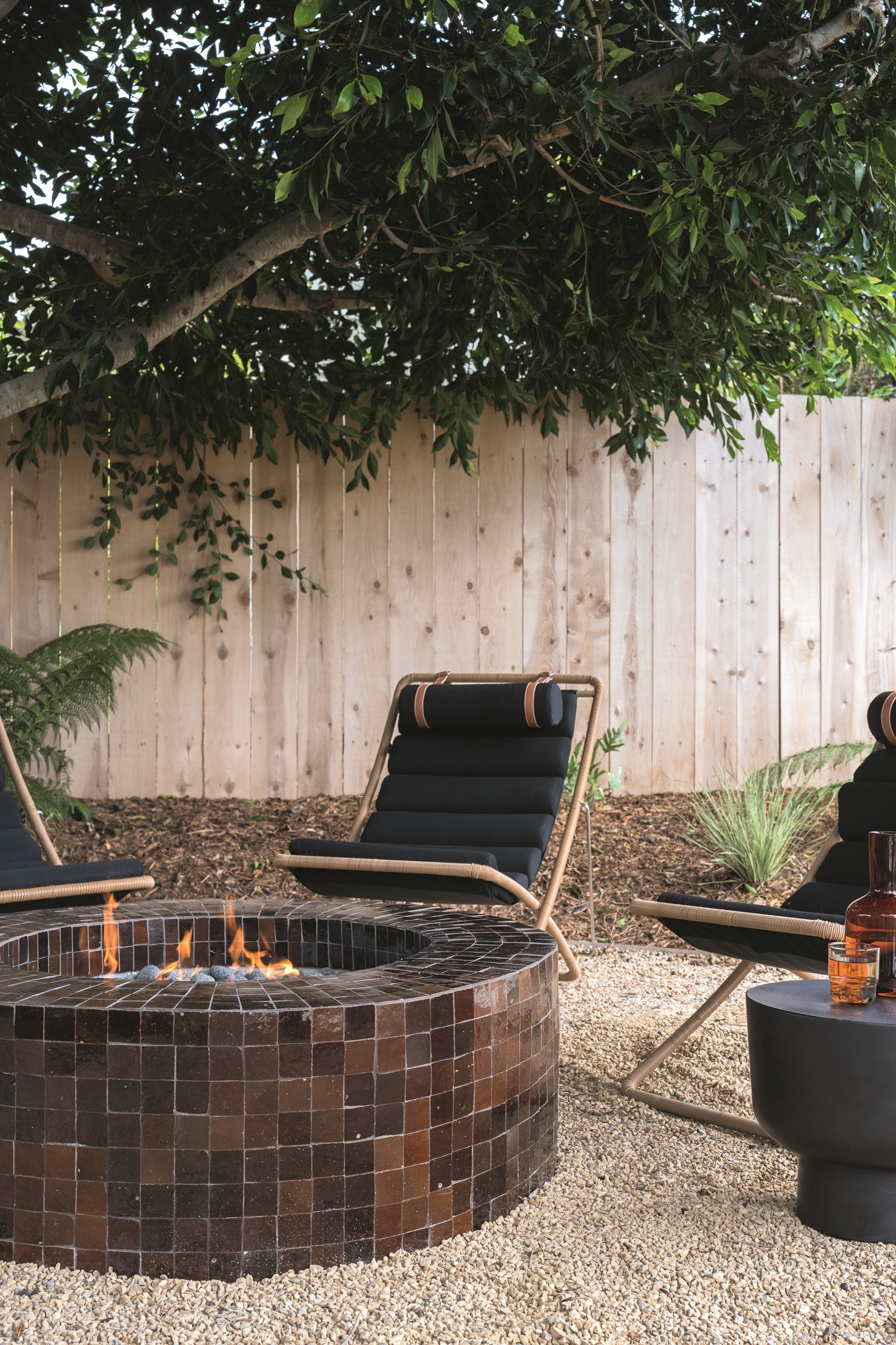 a tiled firepit in a garden surrounded by chairs