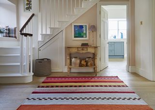wide pink hallway with white stairs and rug