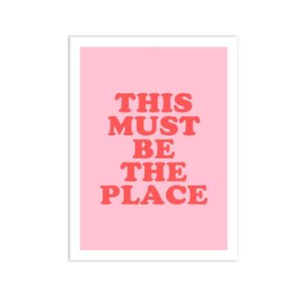 A pink wall artwork that says 'this must be the place'