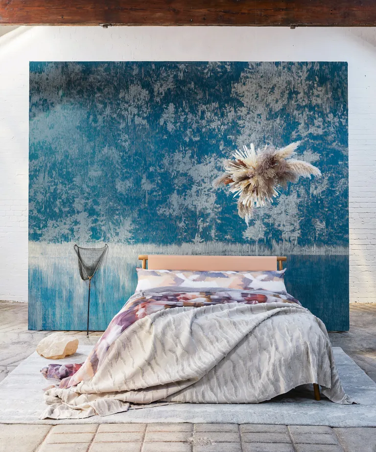 A bedroom with a large abstract canvas behind the coral and wood-framed bed