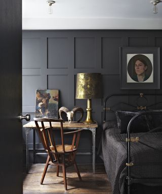 A black bedroom with paneled walls, a wooden desk and a white ceiling