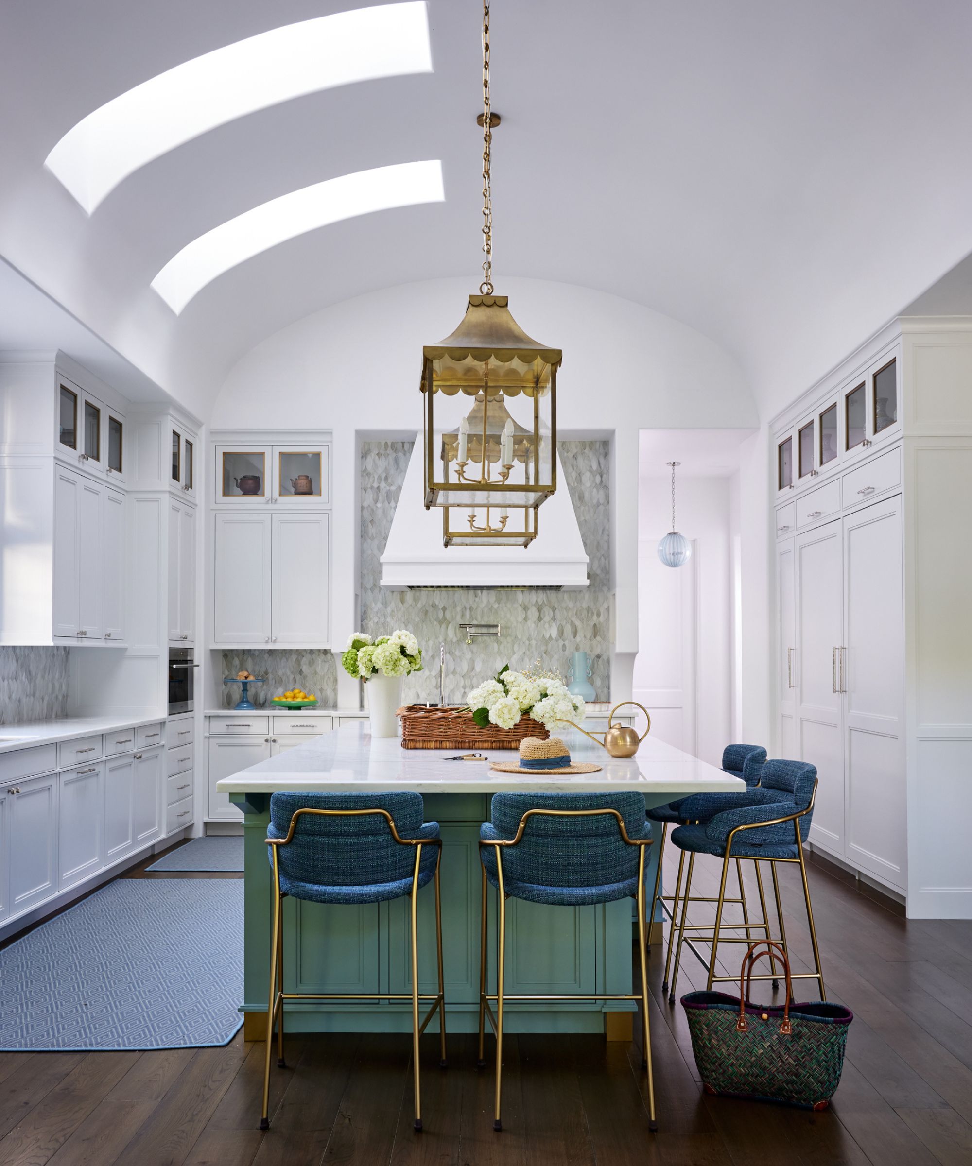White kitchen with white cabinets, a green island and blue seating