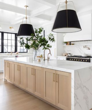 A quartz countertop in a white, wood kitchen with black light fixtures and windowpanes