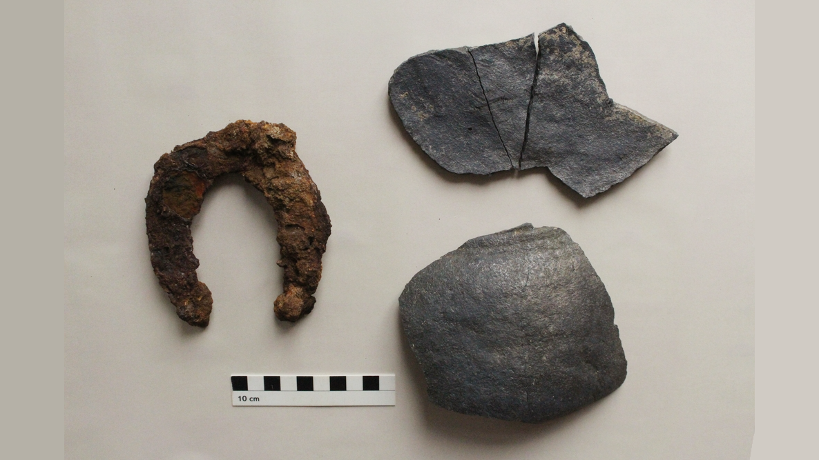 a metal horseshoe and fragments of a ceramic pot