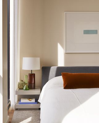 white bedroom with blue headboard and orange cushion
