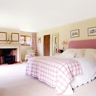 idyllic sussex farmhouse main bedroom with splashes of pink on the headboard curtains and throw
