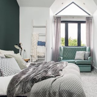 Bedroom with pitched window, green love seat and ladder storage