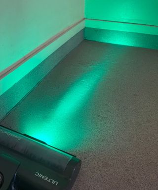 The Ultenic U16 Flex green laser revealing hidden pet hair on hard, gray floor in Bristol Animal Rescue Centre.