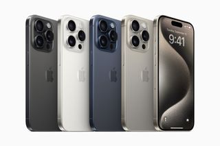 The iPhone 15 Pro Max in all four of its available colors, with the fifth phone in the line-up turned around so the screen is visible. All are set against a white background.