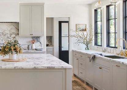 An example of kitchen styles showing a light and airy open plan kitchen with a marble-topped island and cream cabinets