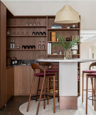 bar with walnut cabinetry and shelves with high round bar table and stools