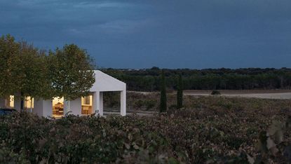 Casa Primitiva, an all white house in spain, seen among greenery and dusk skies