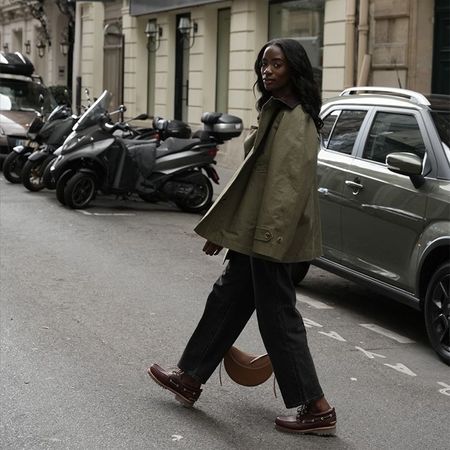 liv wears a green barn jacket, black trousers, and brown shoes and bag